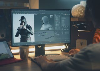 A video game designer works with a 3D character model on a monitor.