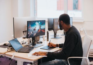 A game developer works on a new game’s visual design at his desk.