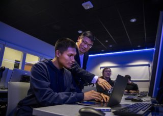 Alan Wang works with a student on his class project from the Cyber Range lab.