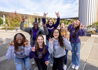 UAlbany students enthusiastically sharing their Great Dane hand signal on the podium