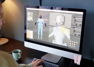 A game designer works on a character model on a computer.