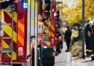 A group of first responders gather next to a line of fire engines to plan an emergency response.