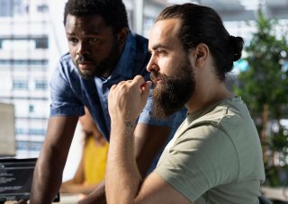 Two ethical hackers review code on a monitor.