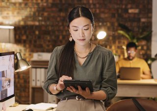 A social media manager works on a tablet in an office.