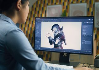A video game designer works on a character model on a monitor.