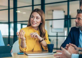 A group of colleagues talking as they sit at a conference table.