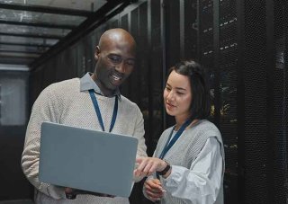Cybersecurity professionals review data on a laptop in a data center.