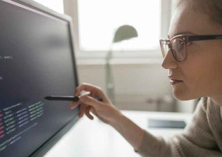 A cybersecurity professional analyzes code on a monitor.