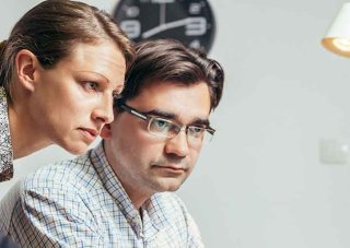 Two cybersecurity analysts in an office review an issue.