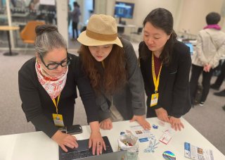 three individuals looking at a laptop