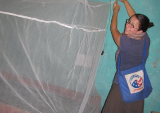 A Peace Corp student hangs netting over a wooden structure.