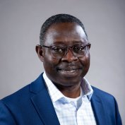 Dr. Alex Kumi-Yeboah with glasses, light blue checked shirt and blue blazer