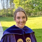 Photo of Mikhaela McFarlin in purple doctoral graduation robes