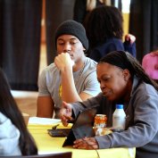 Lakia Green sits at a table with students to demonstrate Microsoft Copilot