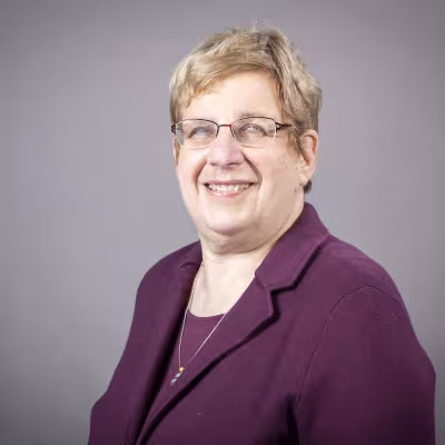 Dr. M. Dolores Cimini headshot wearing purple blazer.