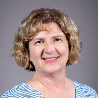 Julie Heslin Pokat, white woman with sandy blonde and brown eyes, with an inviting smile.