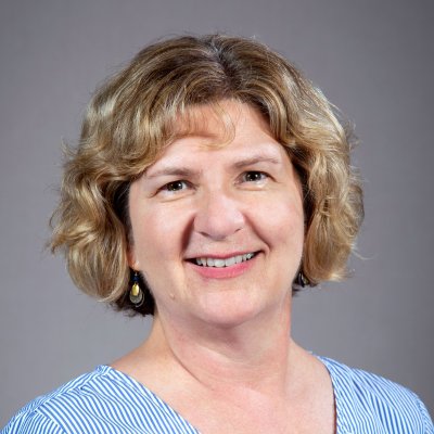 Julie Heslin Pokat, white woman with sandy blonde and brown eyes, with an inviting smile.