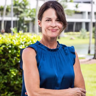 Dr. Kristen C. Wilcox outside smiling posing with arms crossed in blue top
