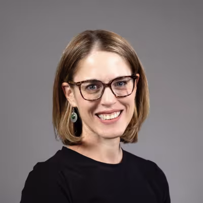Dr. Callen Fishman portrait smiling with glasses and gray background