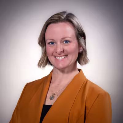 Photo of Megan Cusick Brix in a dark orange blazer