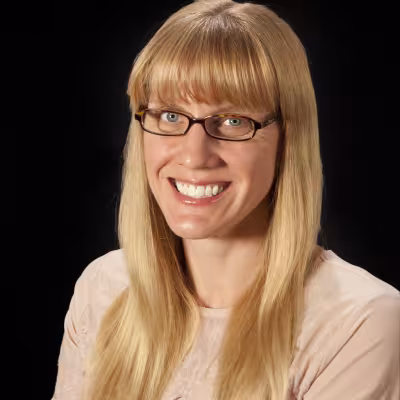 Dr. Erica Barnes smiling with glasses long blonde hair black background