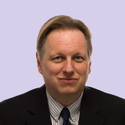 individual in suit smiling with light purple portrait background