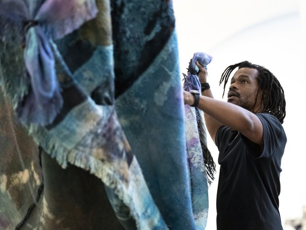 Artist Noel W Anderson installing tapestry