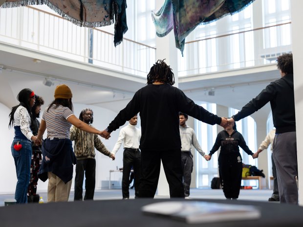 People holding hands in a circle standing within the art museum.