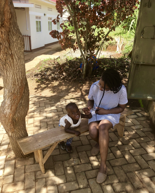 Jenee sitting on a bench in Uganda with a small child.
