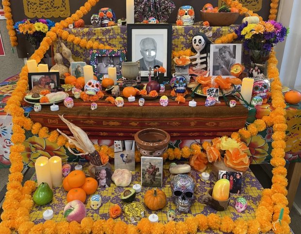 A colorful Day of the Dead altar is draped with orange marigold garlands, candles, gourds, hand-painted skulls, photos and other items in remembrance of lost loved ones.