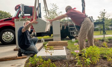 Contractors work together to install the 9/11 memorial bench on the new walking path to ETEC.