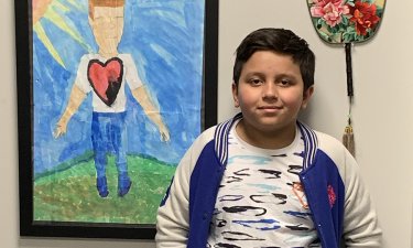 Luis Silva of EJ O'Neal Middle School stands next to a poster he created.