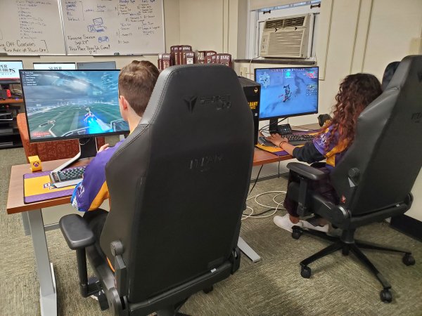 UAlbany eSports students Dylan Tarace and Jesenia Mathew seated at high-performance gaming PCs inside the competitive video gaming arena at Draper Hall.