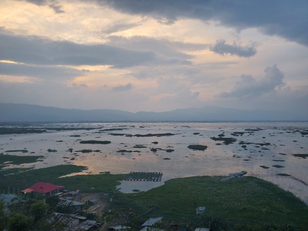 A sunrise through the clouds reflects on Loktak Lake.