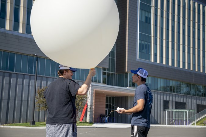 DAES students prepare a weather balloon for a practice launch from the ETEC parking lot.