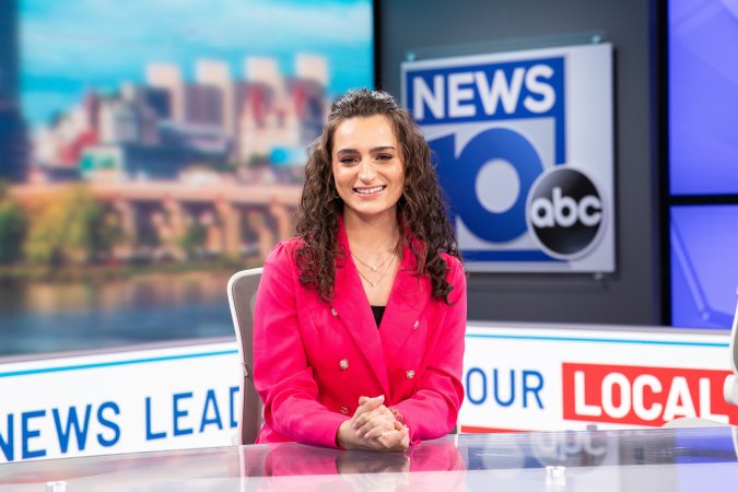 Jordan Due sits at the NEWS10 anchor desk in a pink blazer jacket.