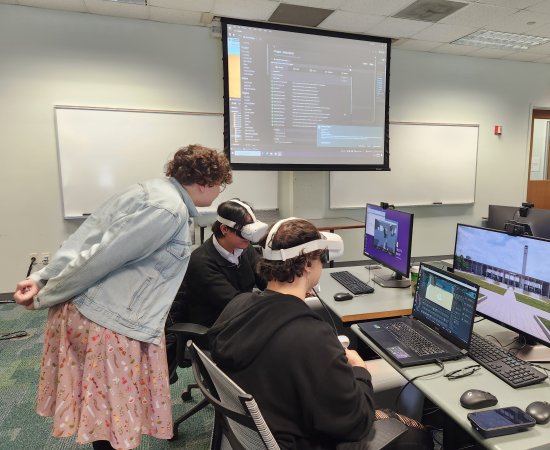 Claire Thomas watches two students play VR games they've created in a computer lab inside the Science Library.