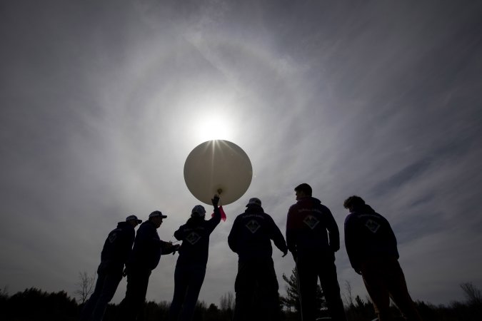UAlbany students prepare to launch a weather balloon in near darkness at Fort Drum.
