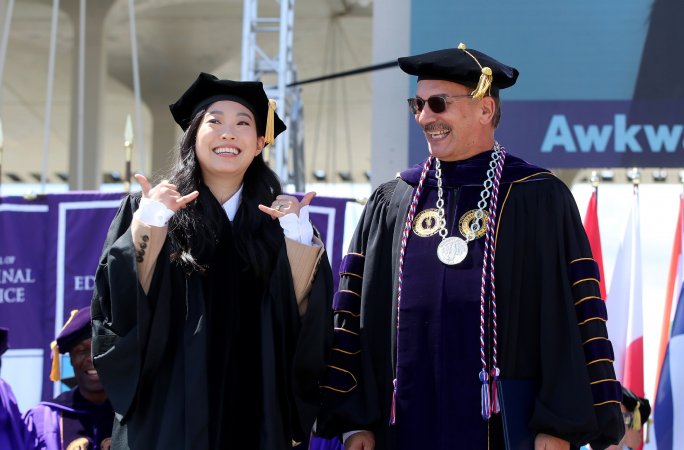 Actress Nora Lum (Awkwafina) stands with President Rodriguez on stage at the 2024 undergraduate commencement ceremony.