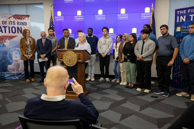 U.S. Senator Kirsten Gillibrand stands with students behind the podium at the CEHC Ops Command Center.