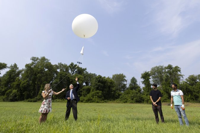 Michelle Campbell and Sen. Jim Tedisco launch a weather balloon into the sky from a field at Hudson Crossing Park.