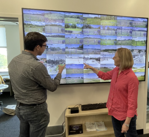Nick Bassill and Jeannette Sutton review current weather conditions across the state on a display screen at the NYS Mesonet operations center.
