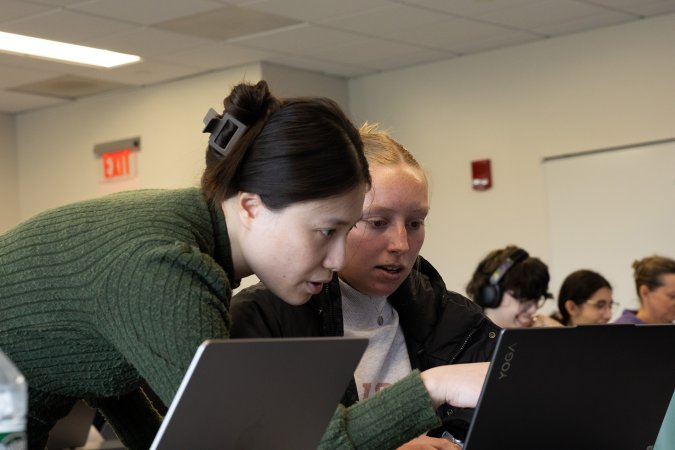 Assistant Professor Zheng Wu reviews environmental data on a student's laptop.