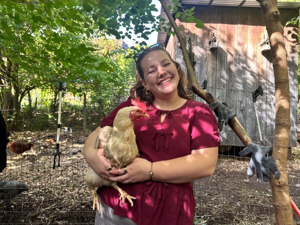Cornell student Charlotte Nelson poses with a chicken at the Radix Center.