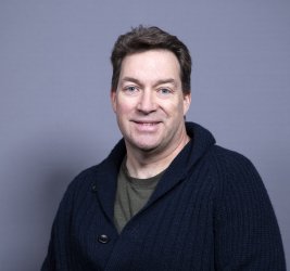 Dr. Backenson smiles at the camera against a grey background.