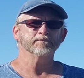 Kevin Quinn with a blue hat, blue shirt and darkened glasses