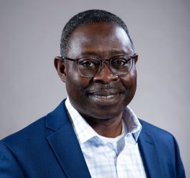 Dr. Alex Kumi-Yeboah with glasses, light blue checked shirt and blue blazer