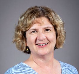 Julie Heslin Pokat, white woman with sandy blonde and brown eyes, with an inviting smile.