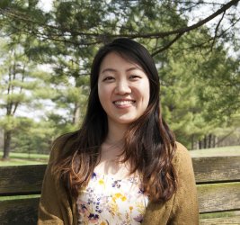 Dr. Haesol Bae smiling outside on a park bench long brown hair flowered shirt tan cardigan sweater