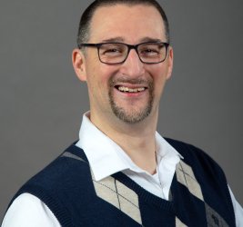 Dr. Timothy "Julio" McLaughlin portrait smiling with glasses and sweater vest